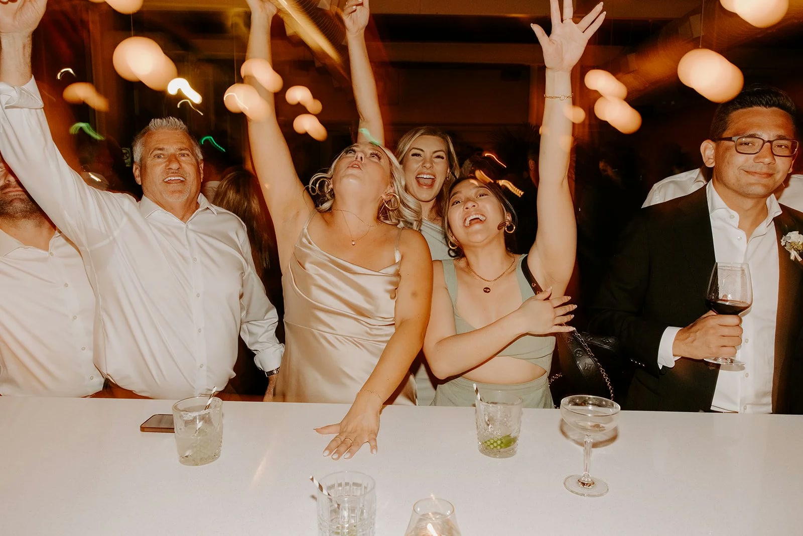 Wedding guests celebrating and toasting at the bar during a reception